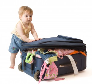 Baby standing near the suitcase