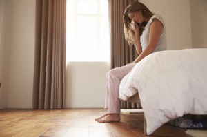 Woman Suffering From Depression Sitting On Bed And Crying