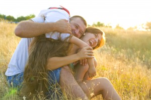 Laughing group of three sitting outdoors on a field